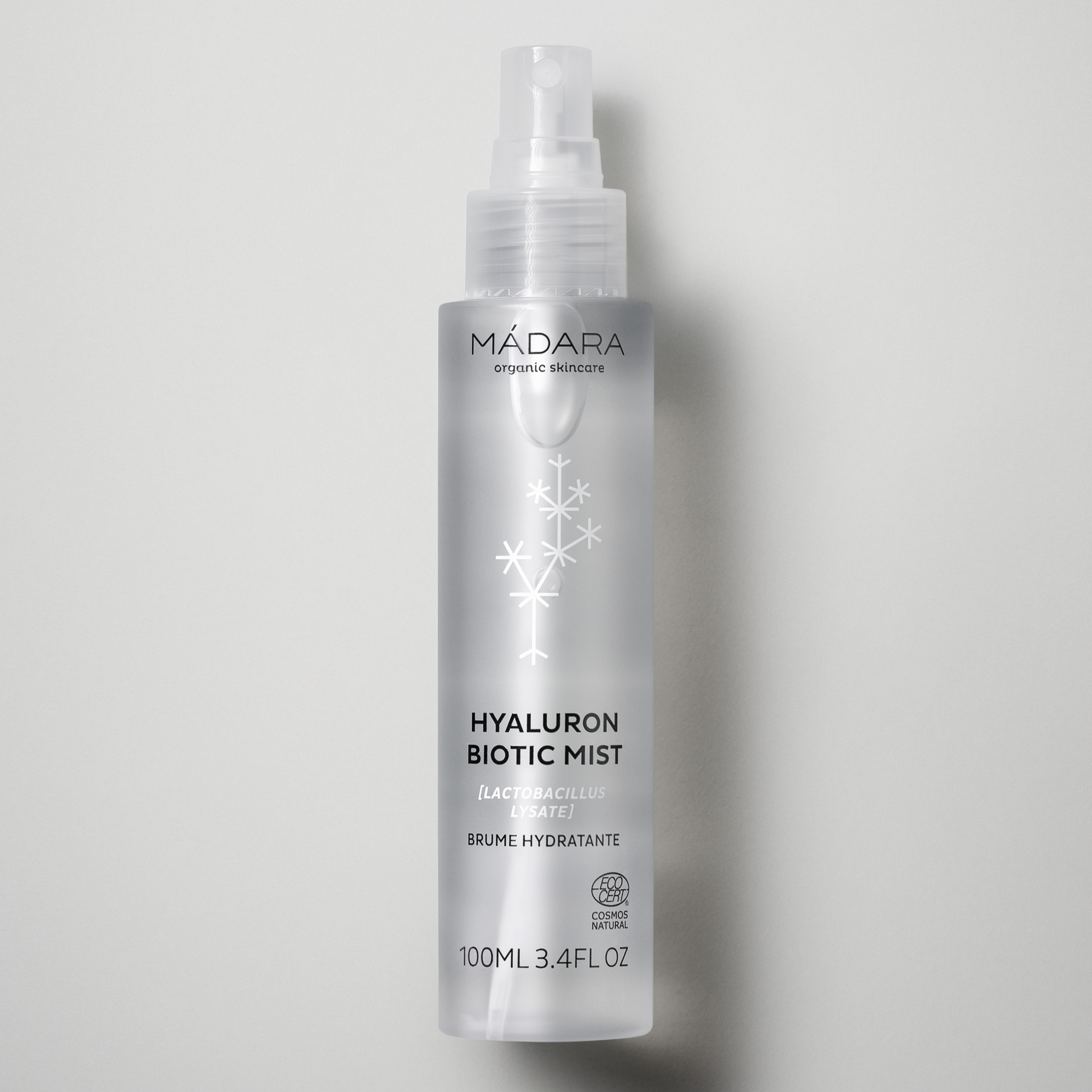 Madara Hyaluron Biotic Mist – doorzichtige sprayfles van 100 ml met wit hyaluron-molecuul-motief op grijze achtergrond, hydraterende gezichtsspray met hyaluronzuur.
